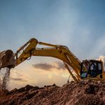 Excavator at a construction site against sunset sk
